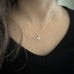 sterling silver dove necklace with a white topaz set in the center and free floating on a circle that moves on its bail.